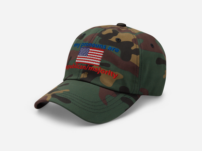 A green camouflage dad hat featuring "my pronouns are republican/majority" embroidery with detailed a American flag design, shown from the left-front angle, emphasizing the clean, adjustable strap, structured fit and highlighting the curved brim and stitching details