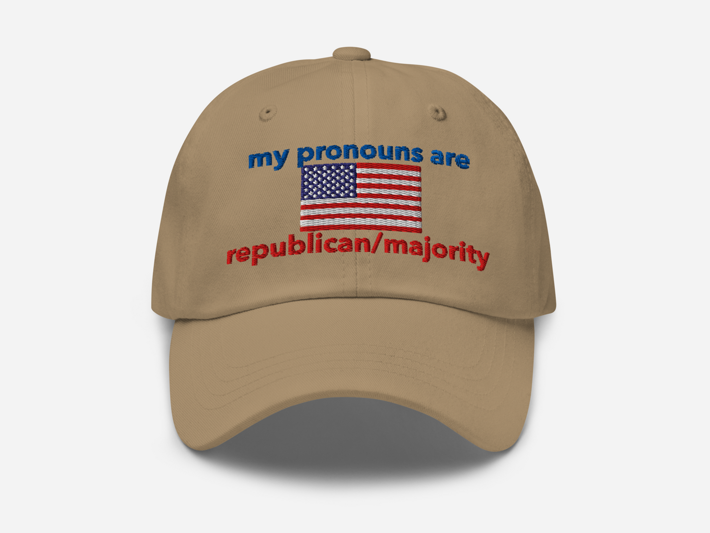 A khaki dad hat with the embroidered text "my pronouns are republican/majority" in bold red and blue, featuring a detailed American flag design at the center, viewed from the front