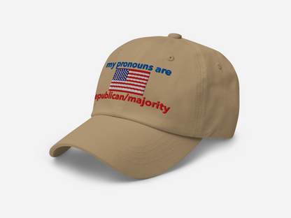 A khaki dad hat featuring "my pronouns are republican/majority" embroidery with detailed a American flag design, shown from the left-front angle, emphasizing the clean, adjustable strap, structured fit and highlighting the curved brim and stitching details